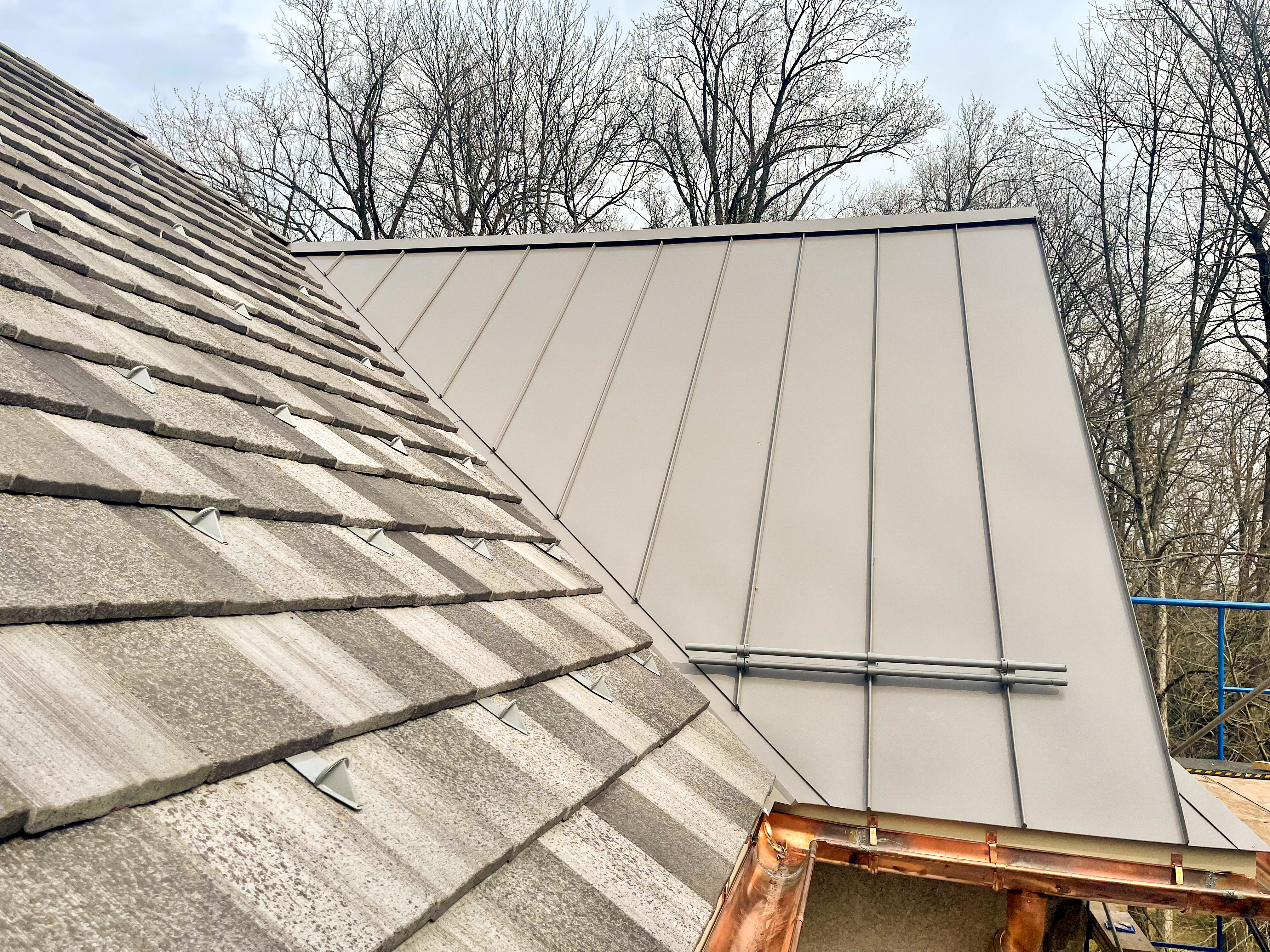 Custom pad and pipe style snow retention system for combination metal and asphalt shingle on residential roof.